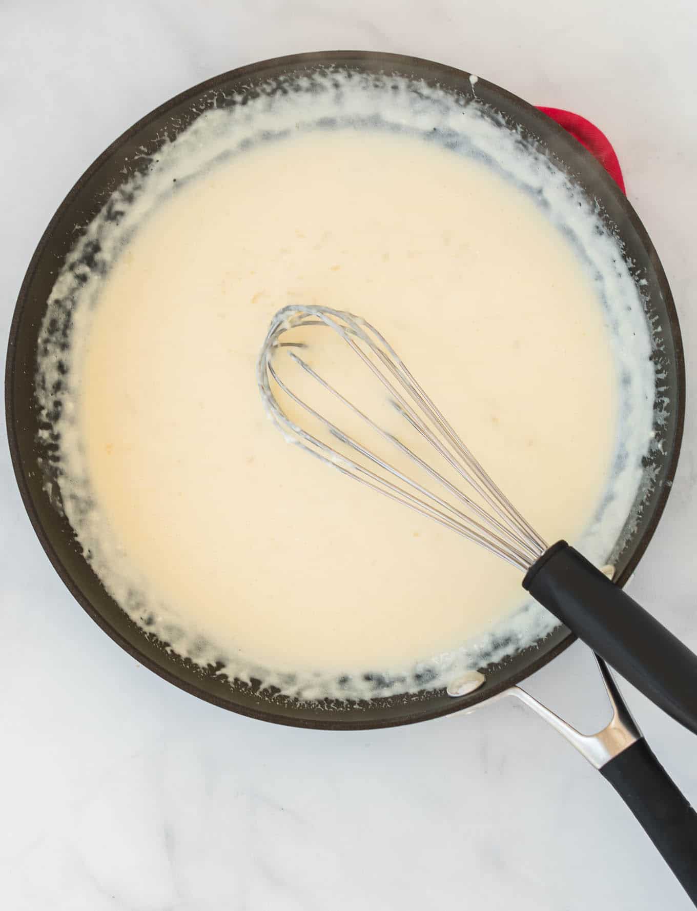 cream cheese pasta sauce in a skillet with a whisk