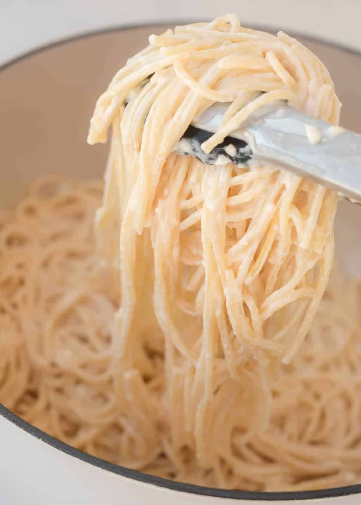 tons grabbing cream cheese spaghetti noodles from the pan
