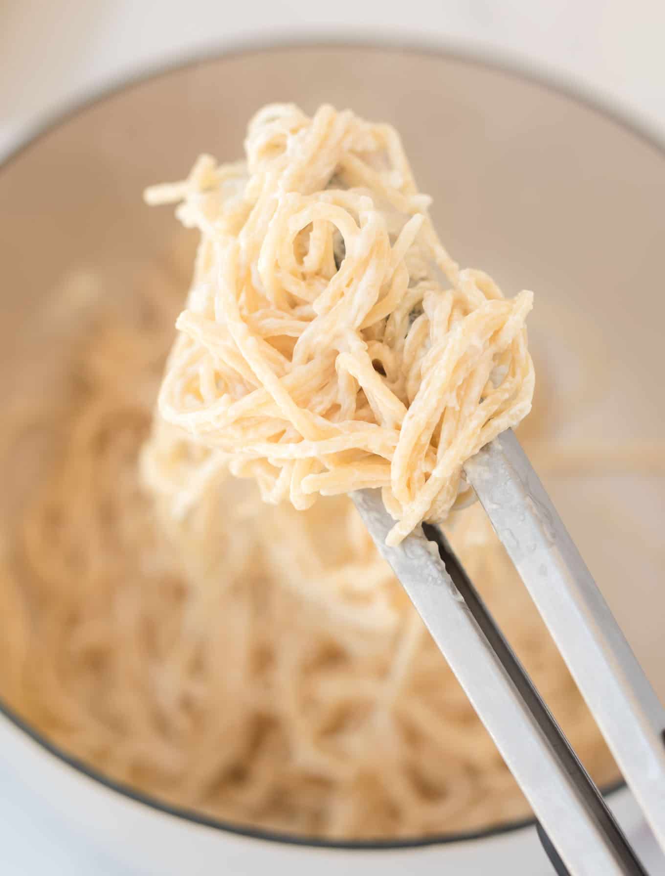 tons grabbing cream cheese spaghetti noodles from the pan