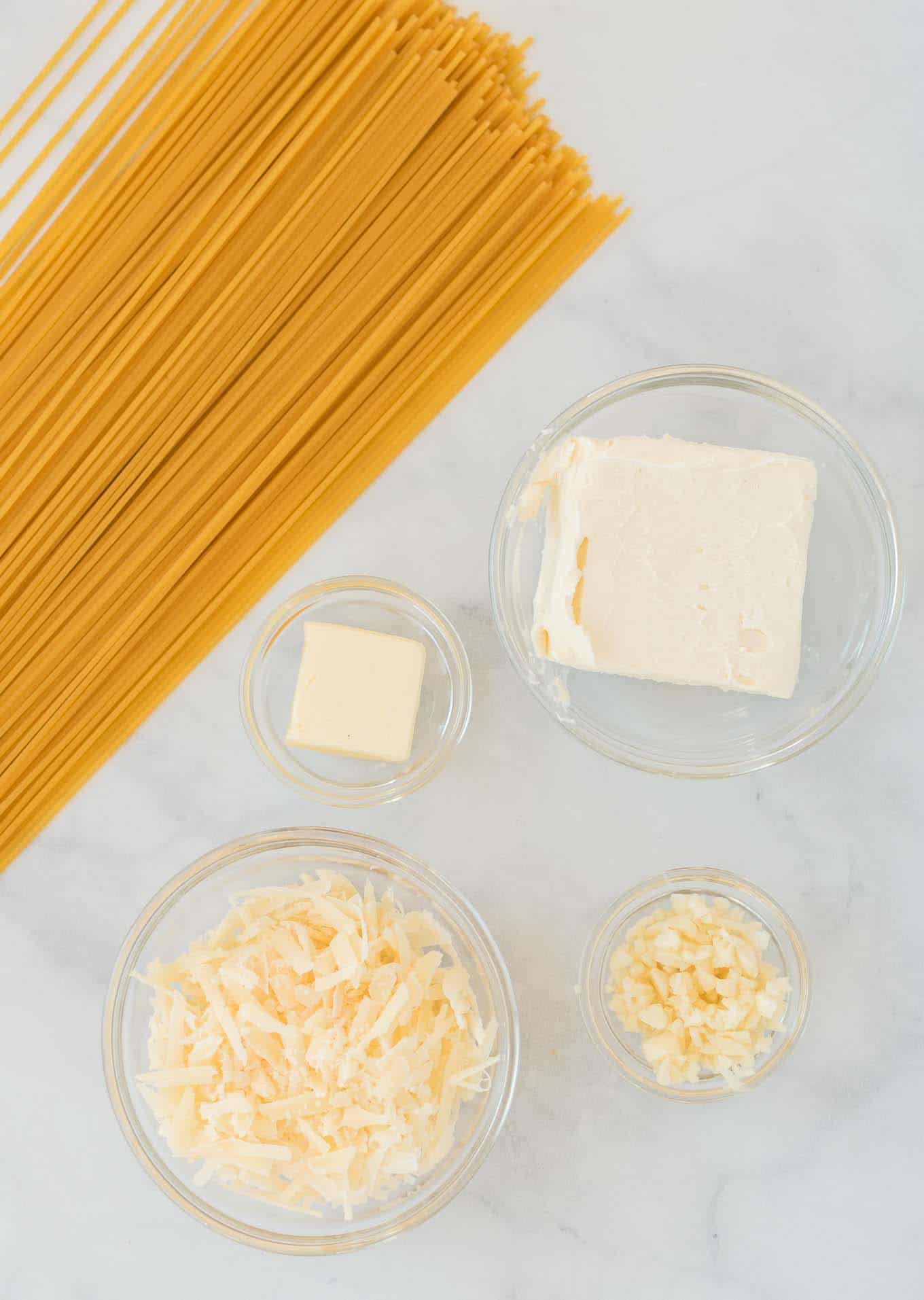 ingredients laid out - spaghetti noodles, butter, garlic, cream cheese, and parmesan