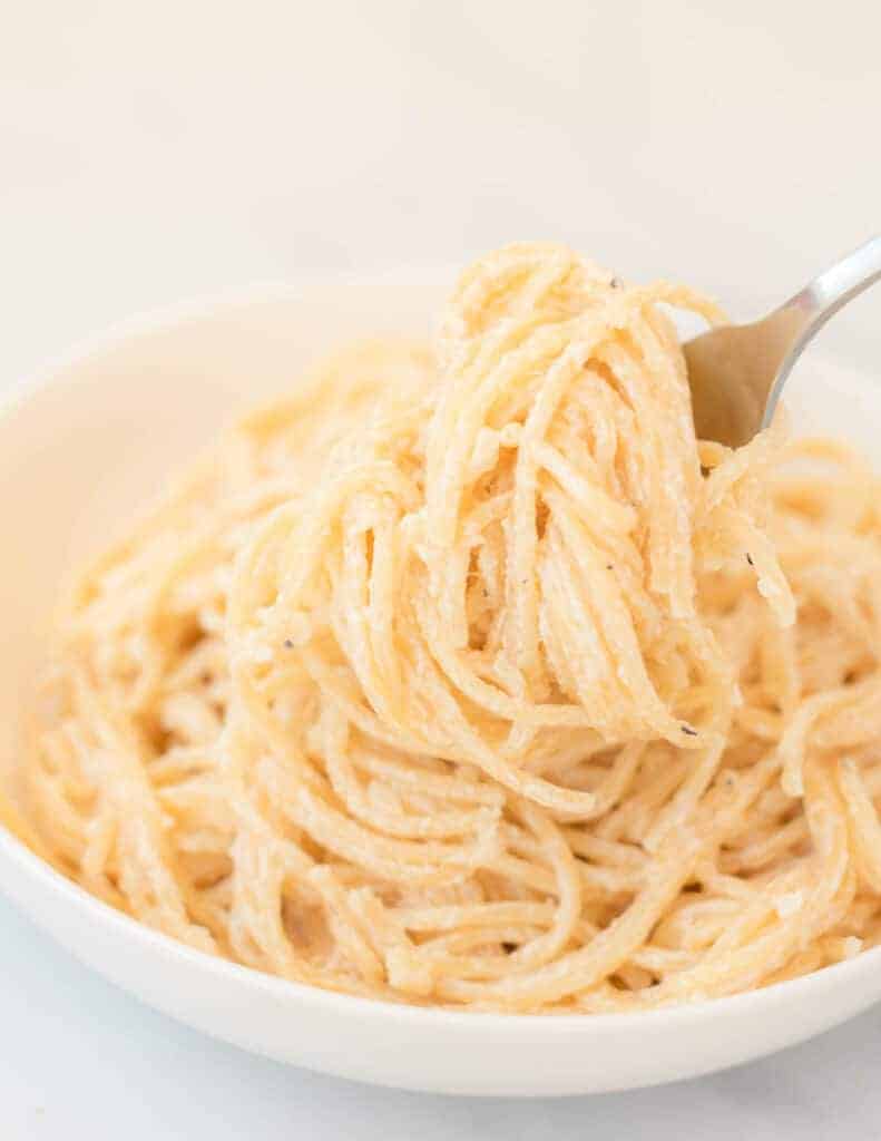 cream cheese pasta in a white bowl with a fork