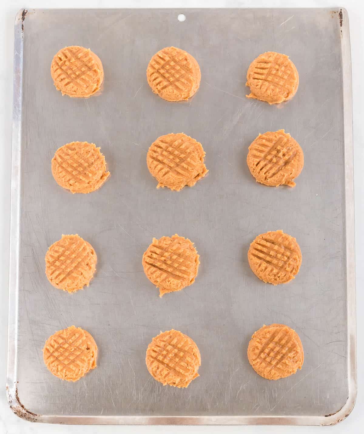 balls of cookie dough pressed with a fork in a crisscross pattern