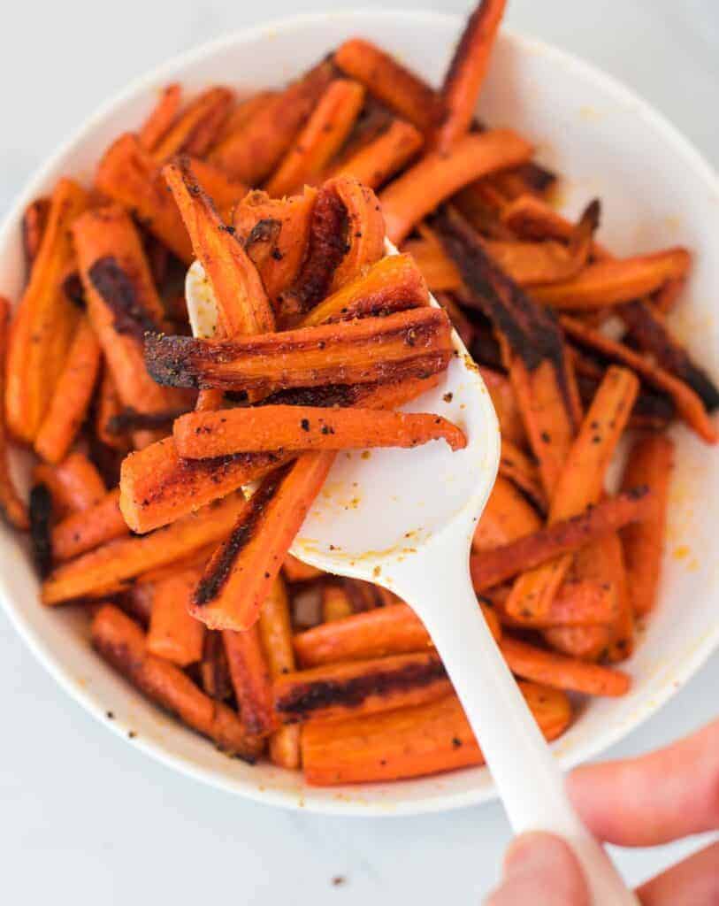 a spoon scooping roasted carrots from a bowl