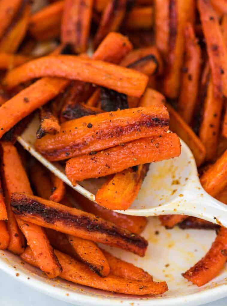 a spoon scooping roasted carrots from a bowl