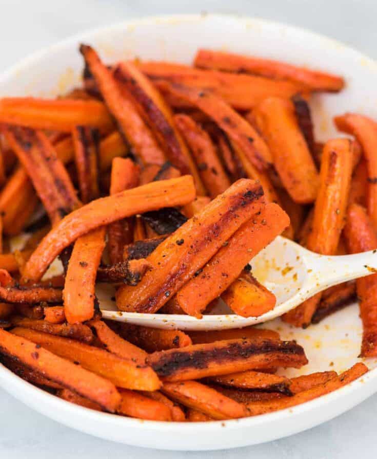 a spoon scooping roasted carrots from a bowl