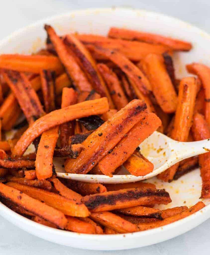 a spoon scooping roasted carrots from a bowl