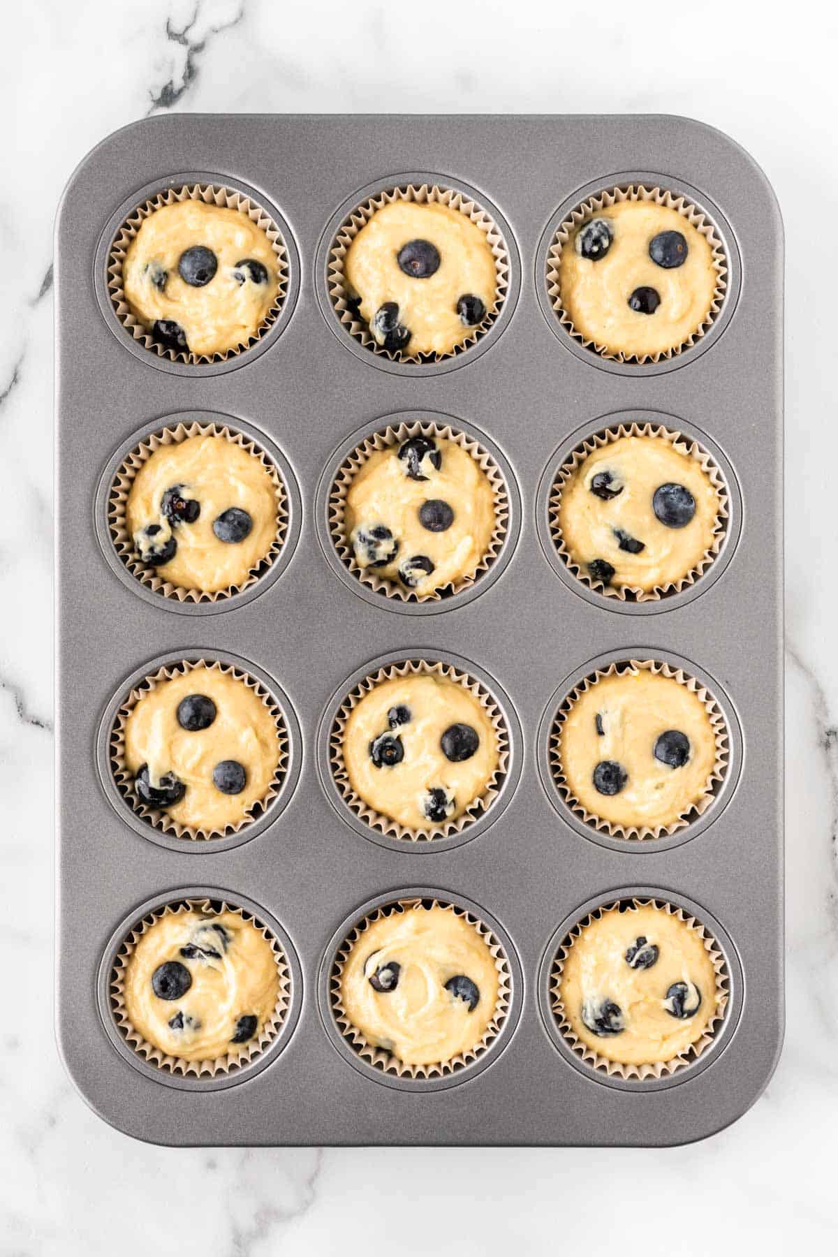filling muffin tins with muffins batter