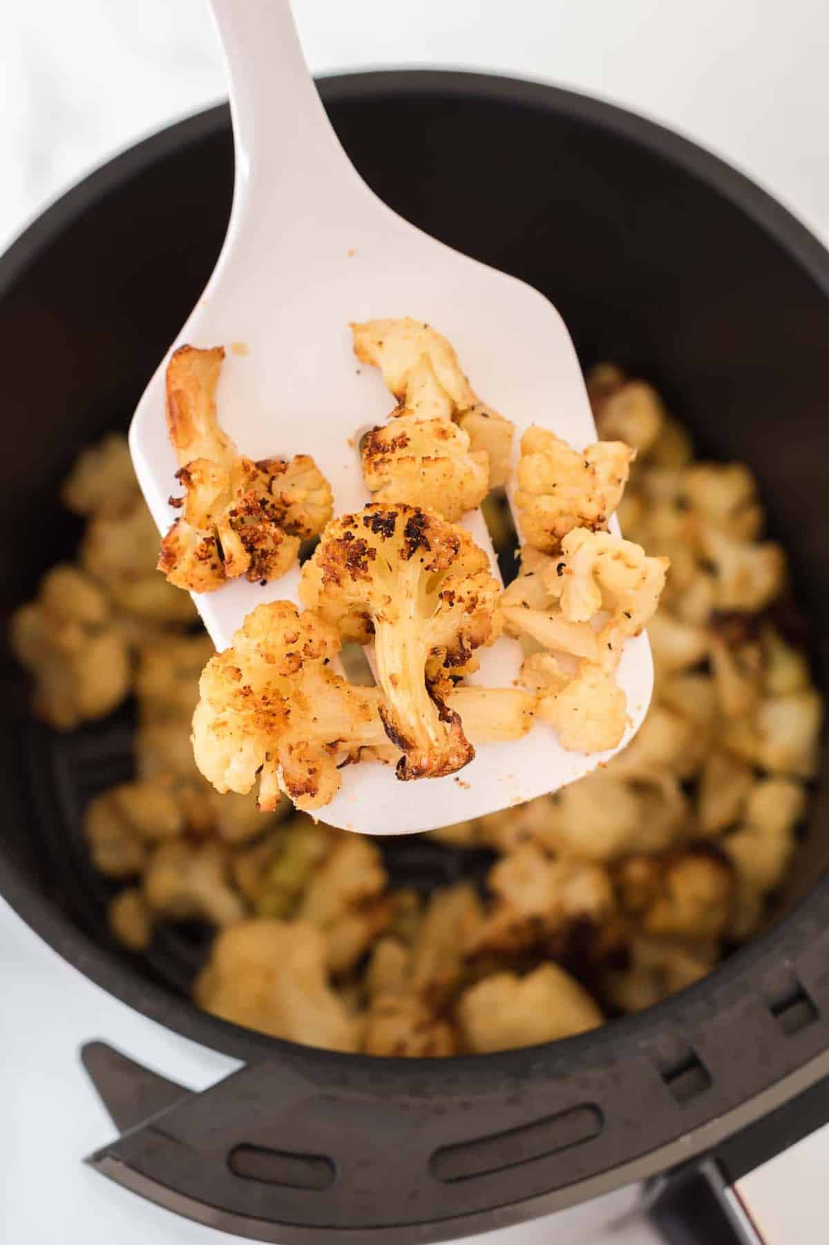 a spatula holding a scoop of air fryer frozen cauliflower