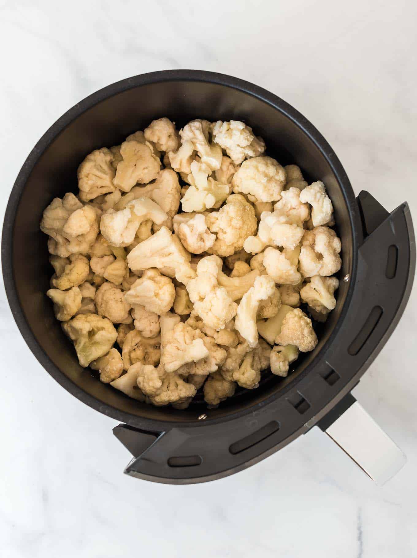 frozen cauliflower in an air fryer basket