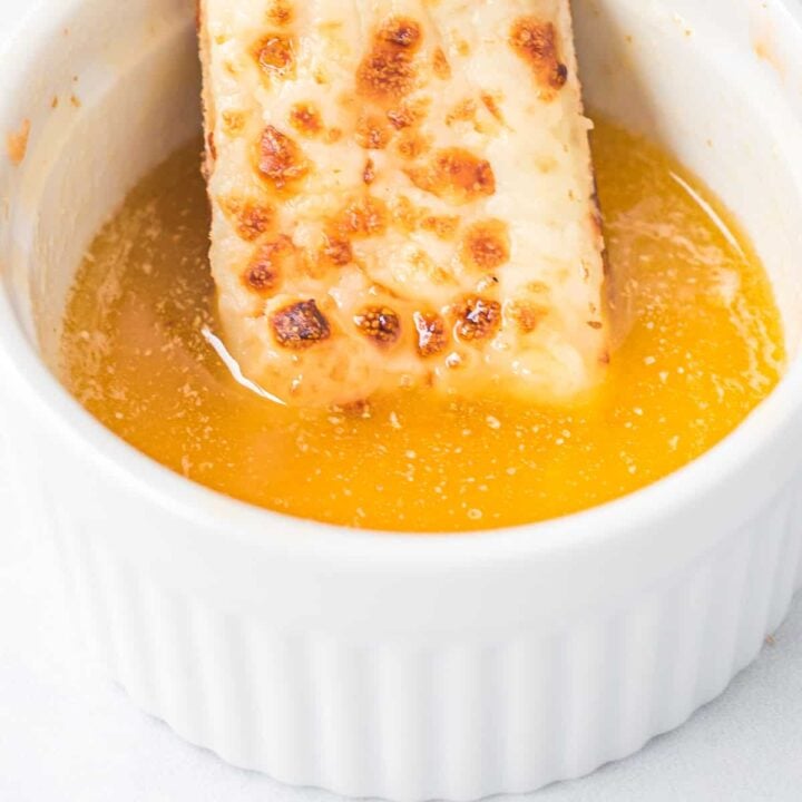 cheese stick being dipped in garlic sauce