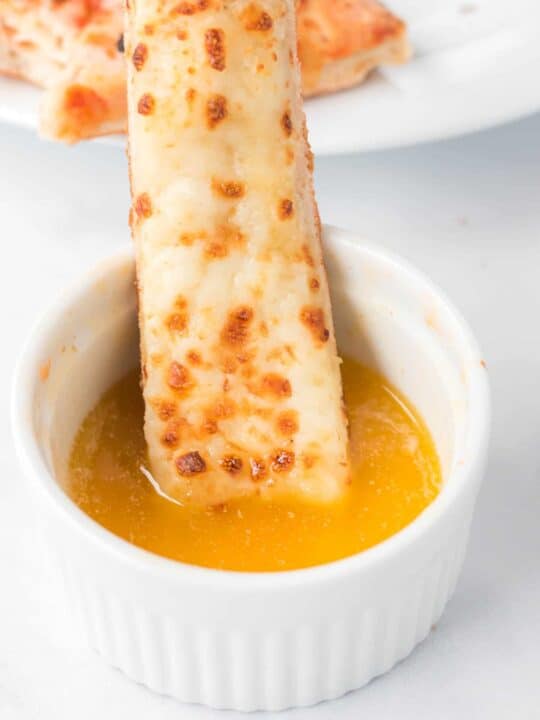 cheese stick being dipped in garlic sauce