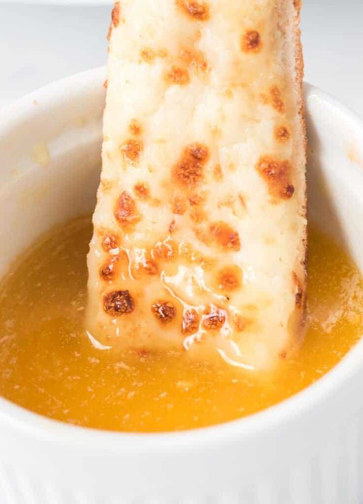 cheese stick being dipped in garlic sauce