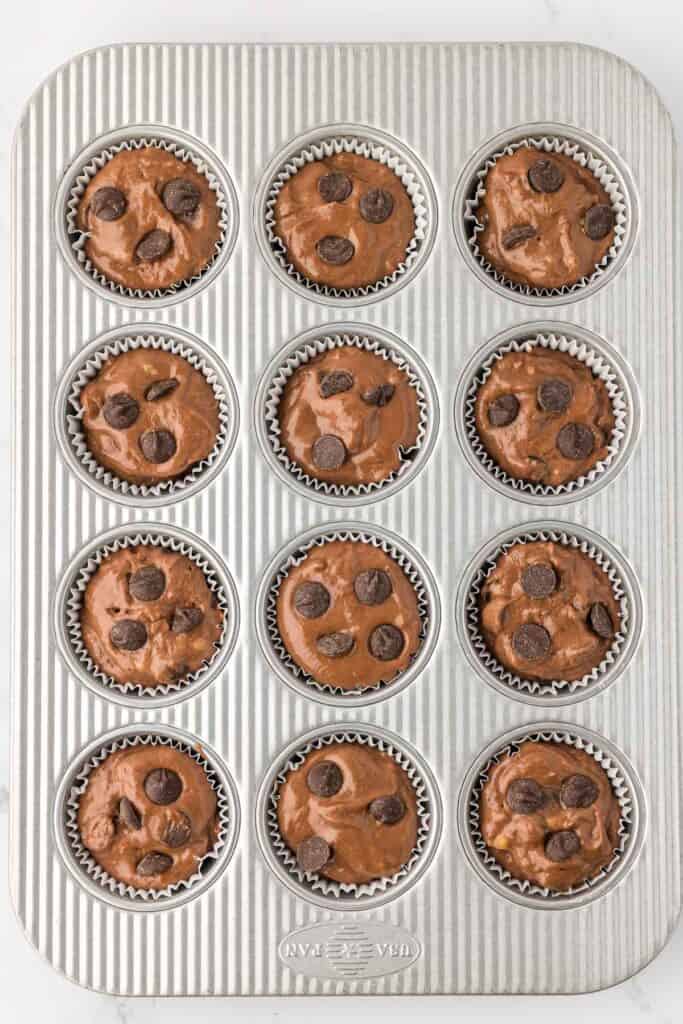 muffin batter in a muffin tin topped with chocolate chips