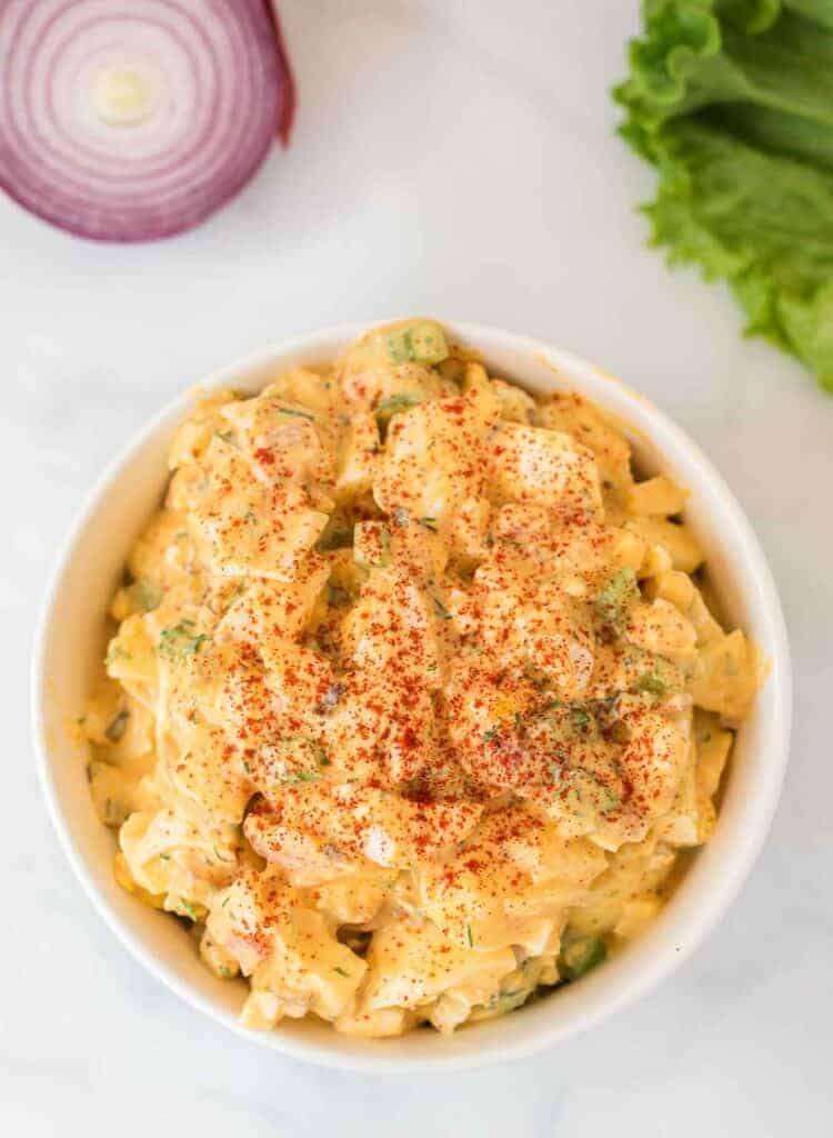 healthy egg salad in a white bowl sprinkled with paprika