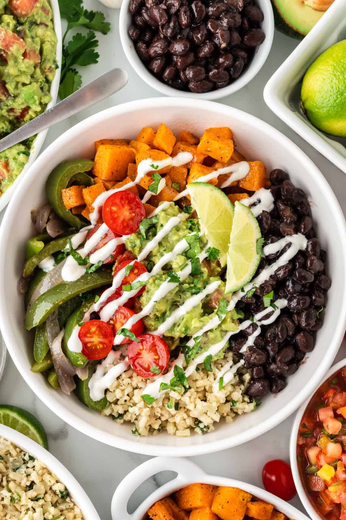 cauliflower rice burrito bowl with black beans, fajita veggies, sweet potatoes, and guacamole