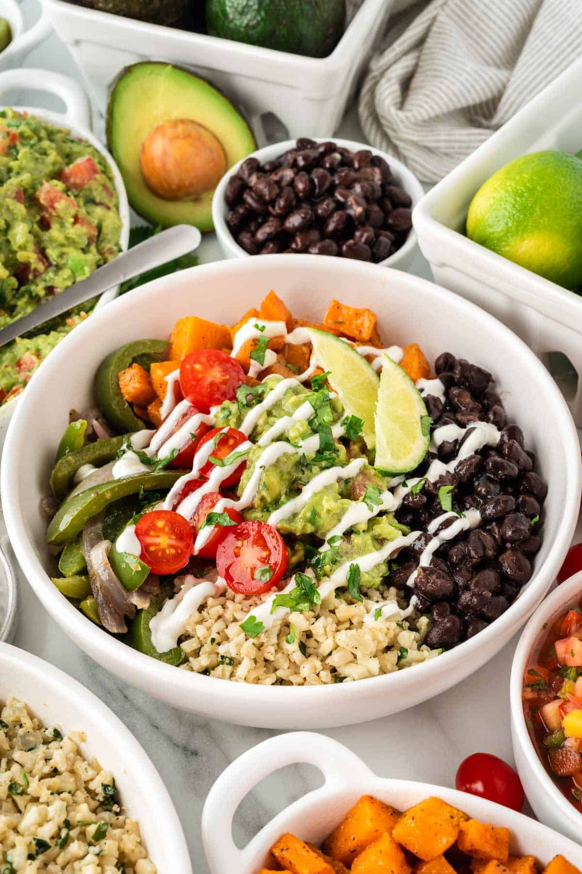 cauliflower rice burrito bowl with black beans, fajita veggies, sweet potatoes, and guacamole