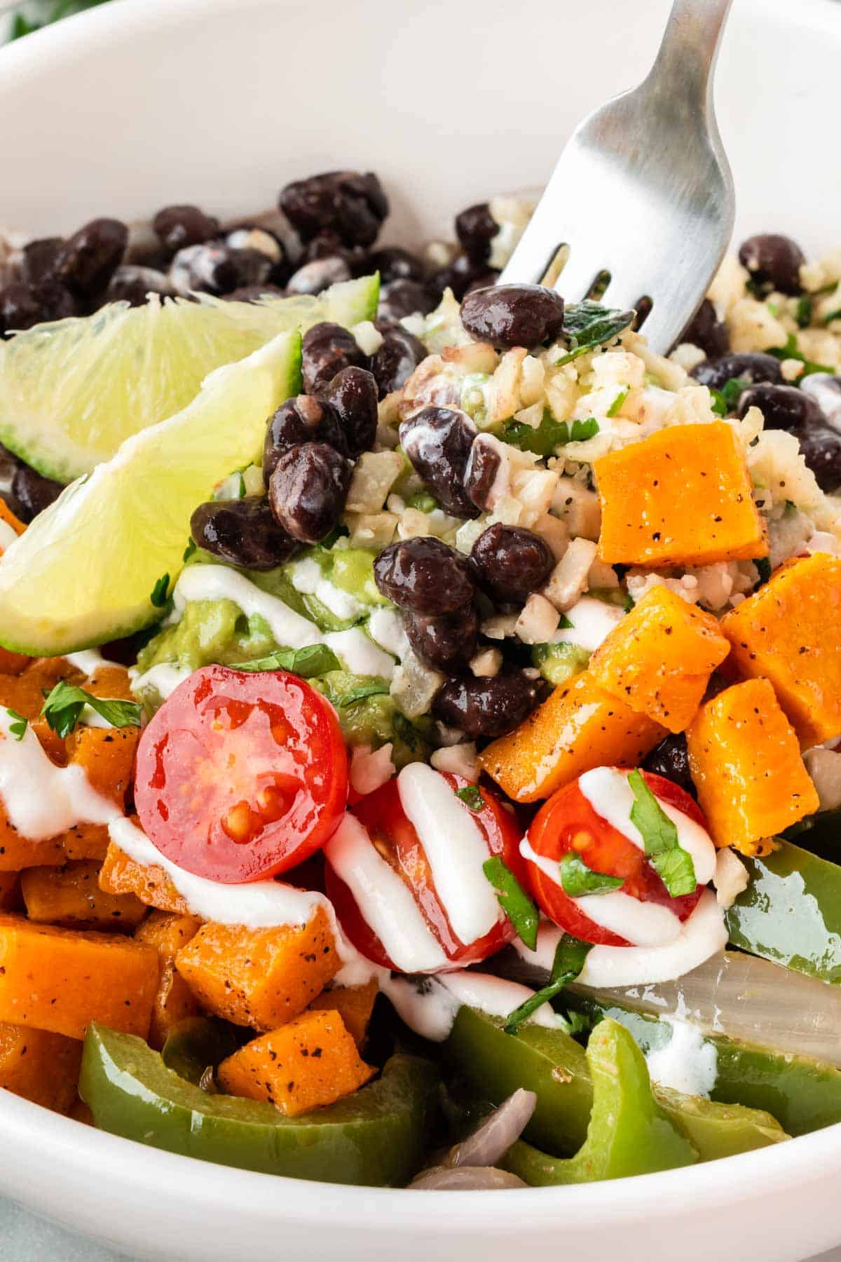 cauliflower rice burrito bowl with black beans, fajita veggies, sweet potatoes, and guacamole