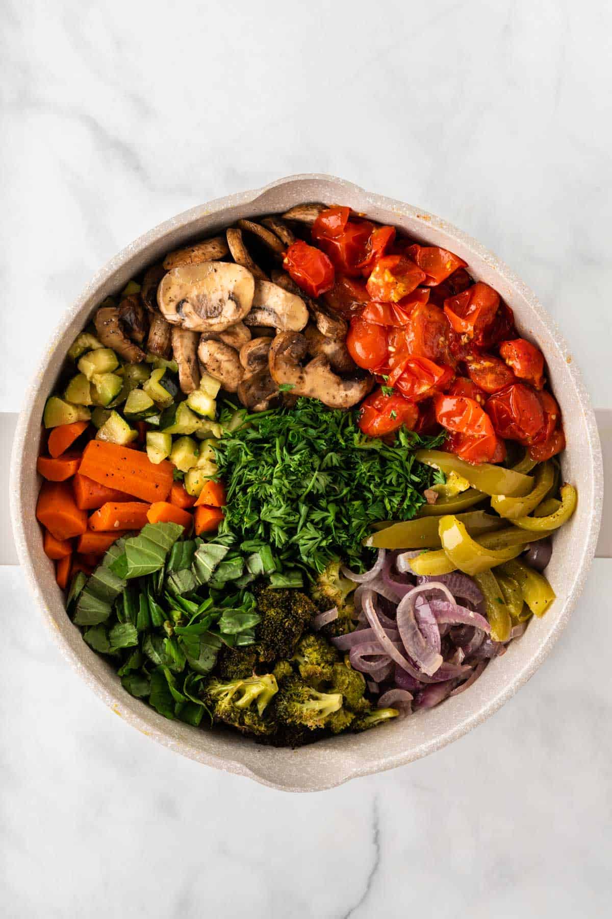 adding the roasted vegetables and herbs to the pasta