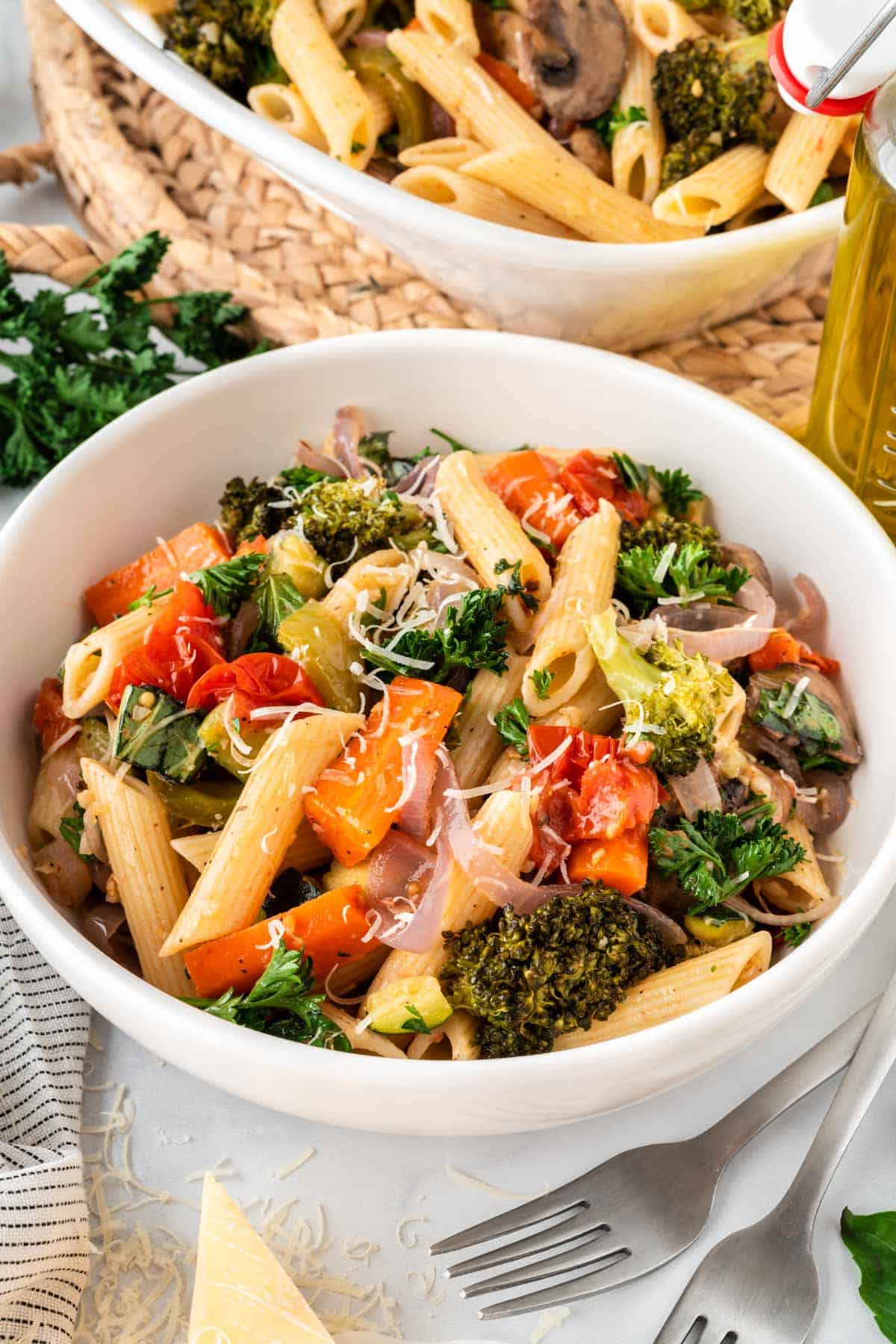 roasted veggie pasta in a bowl topped with parmesan cheese