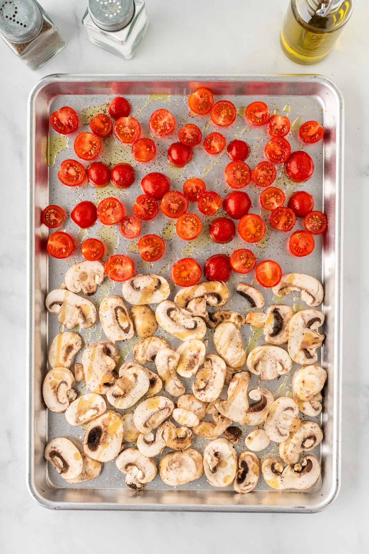 sliced mushrooms and cherry tomatoes on a baking sheet