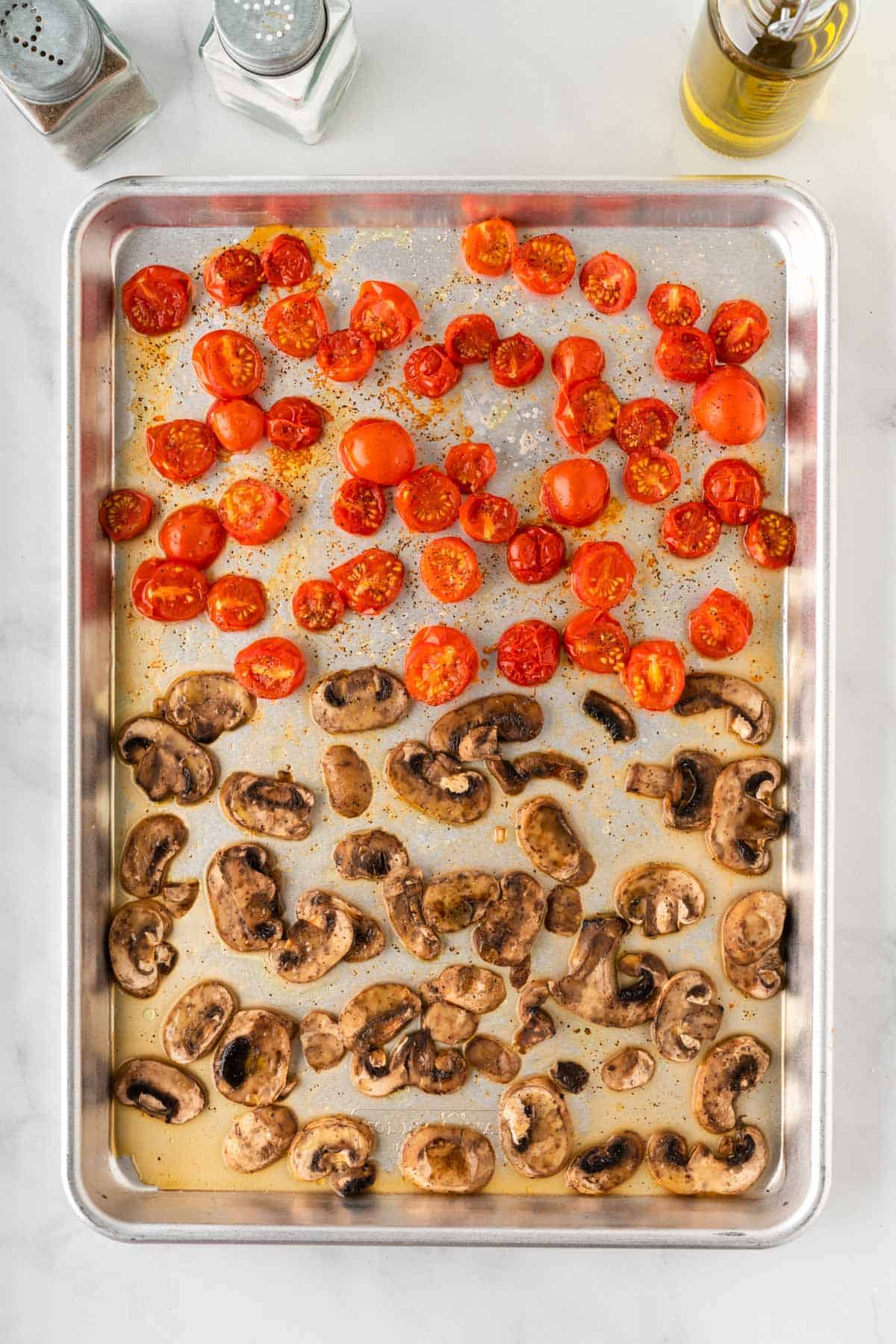 roasted mushrooms and tomatoes on a baking sheet