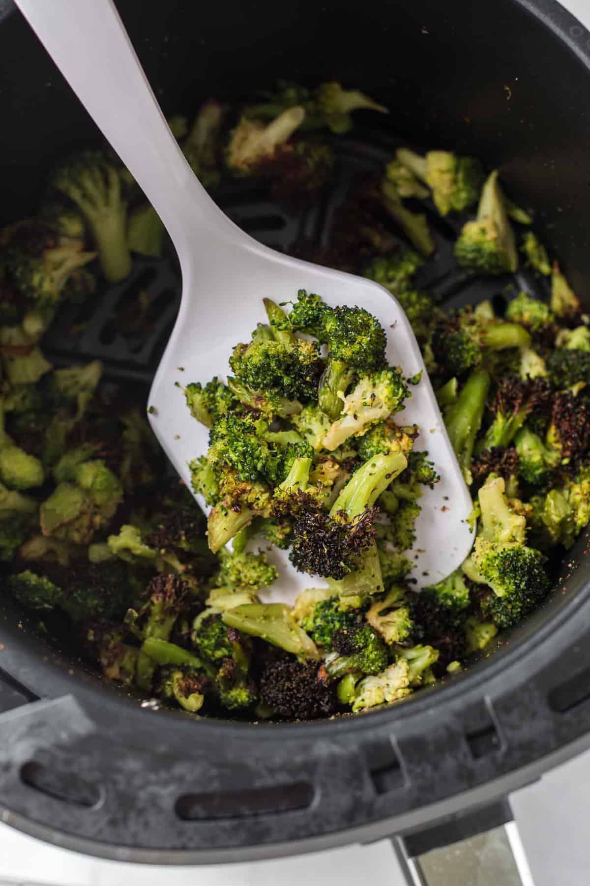 a white spatula with a scoop of roasted broccoli