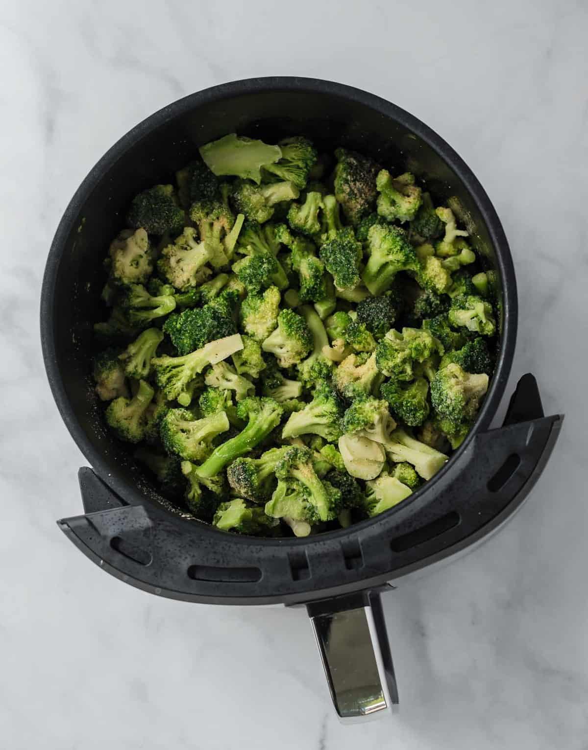 frozen broccoli florets in an air fryer basket