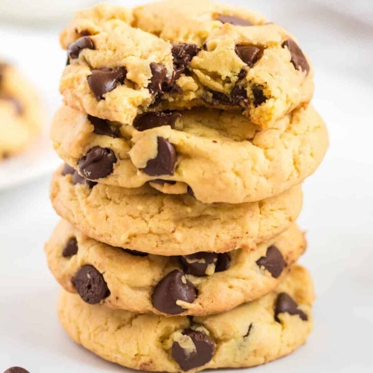stacked chocolate chip cookies with one taken a bite out of