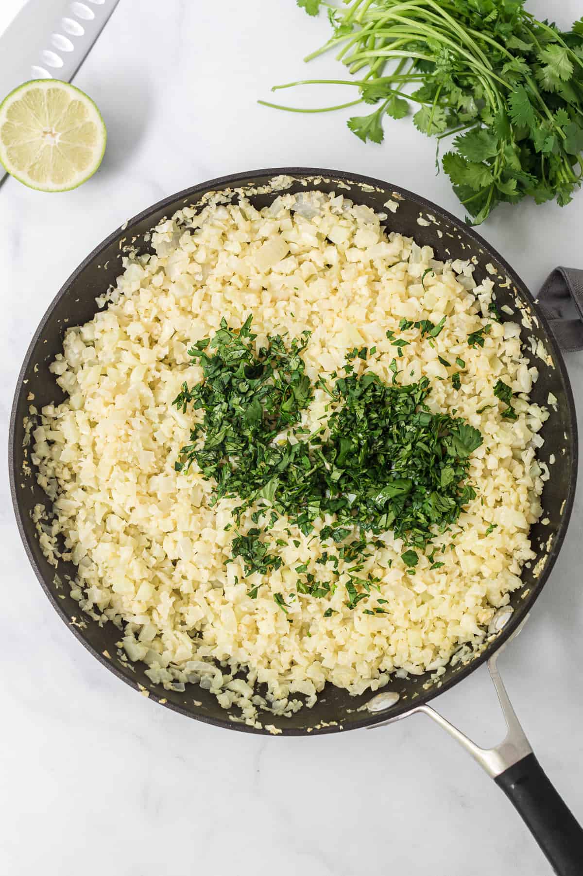 cauliflower rice in a skillet with chopped cilantro on top