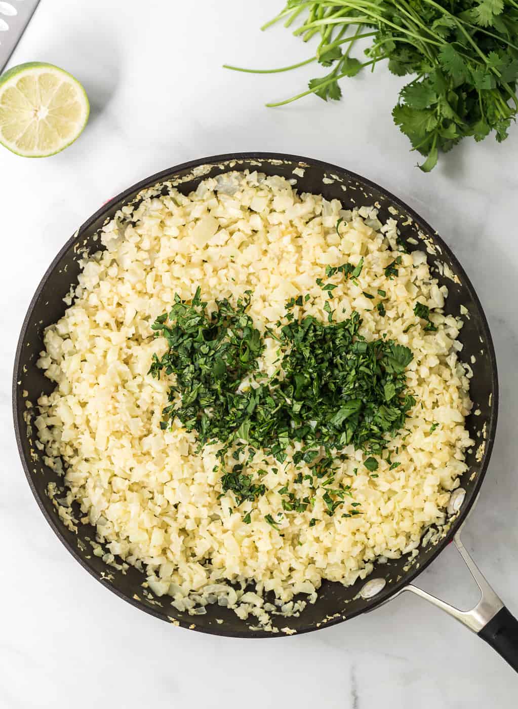 cauliflower rice in a skillet with chopped cilantro on top