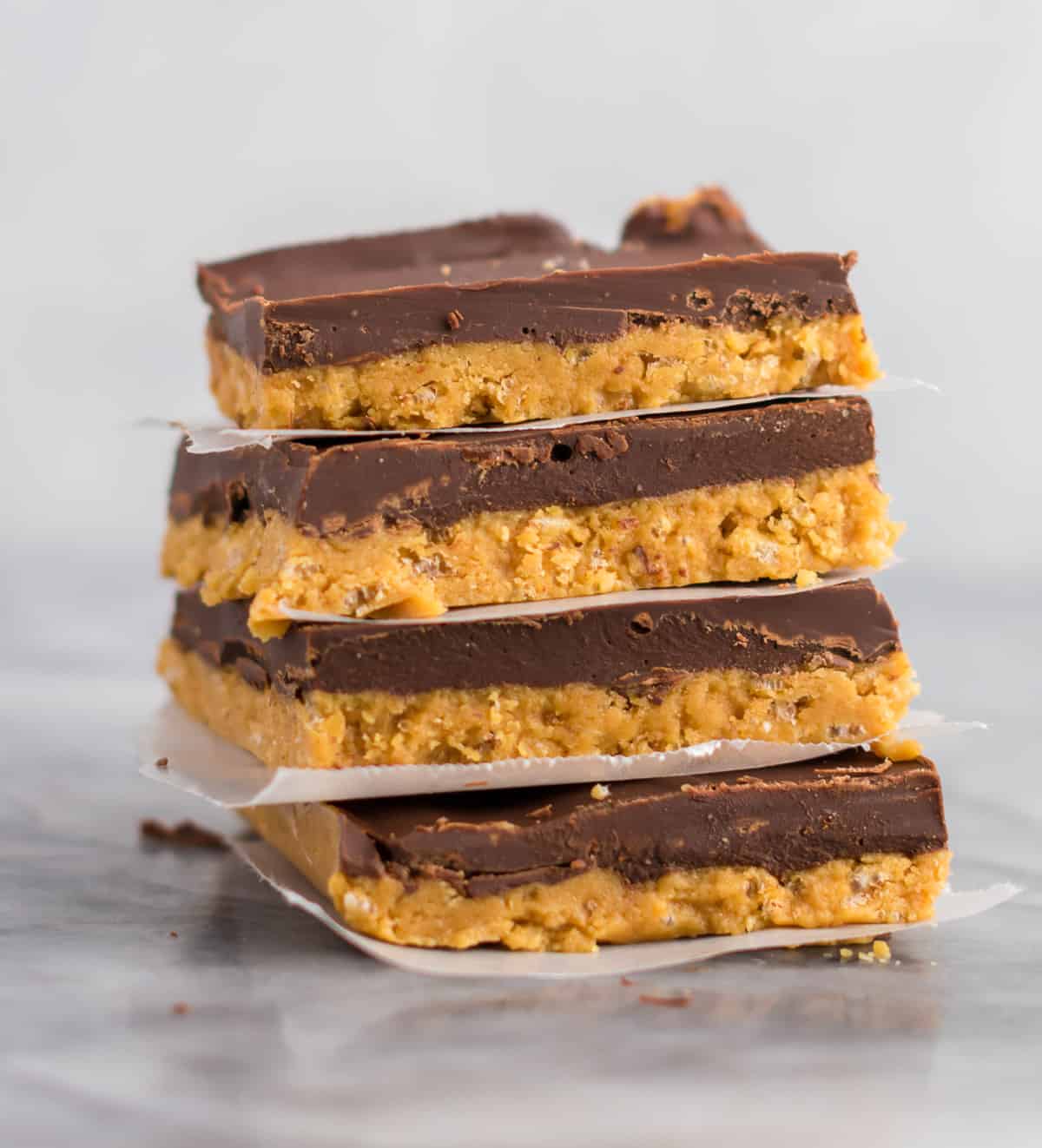 no bake chocolate peanut butter bars stacked between pieces of wax paper