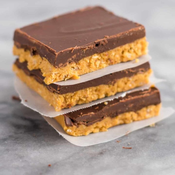 no bake chocolate peanut butter bars stacked between pieces of wax paper