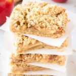 apple crisp bars stacked between squares of parchment paper