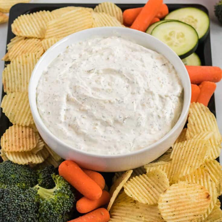 chip dip on a platter with chips and vegetables for dipping