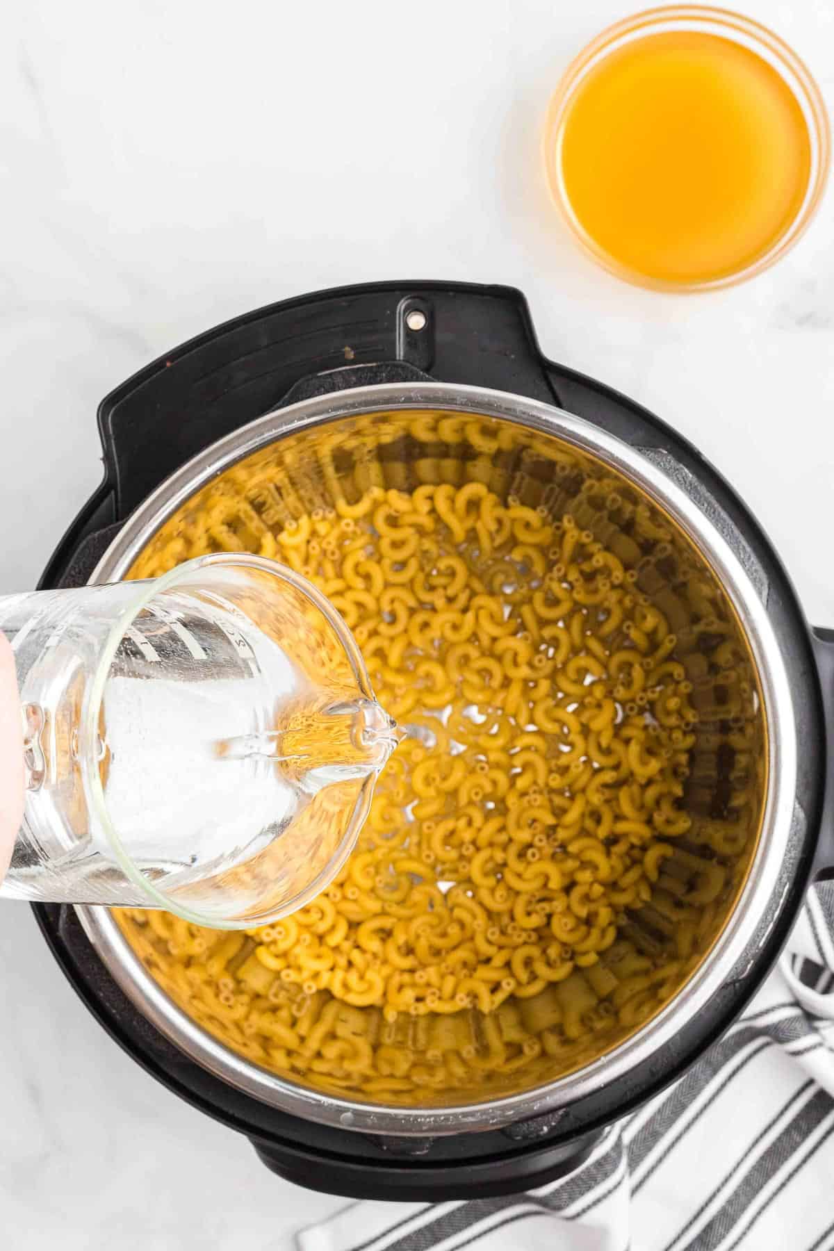pouring water over macaroni noodles in an instant pot