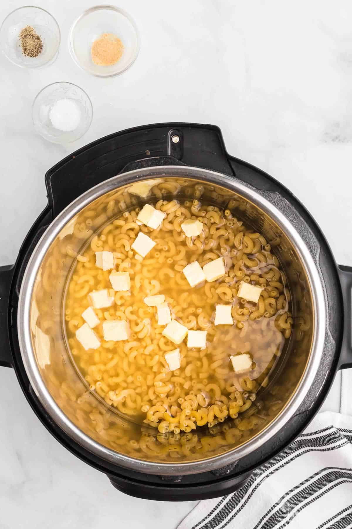 cubed butter and liquid with macaroni in an instant pot