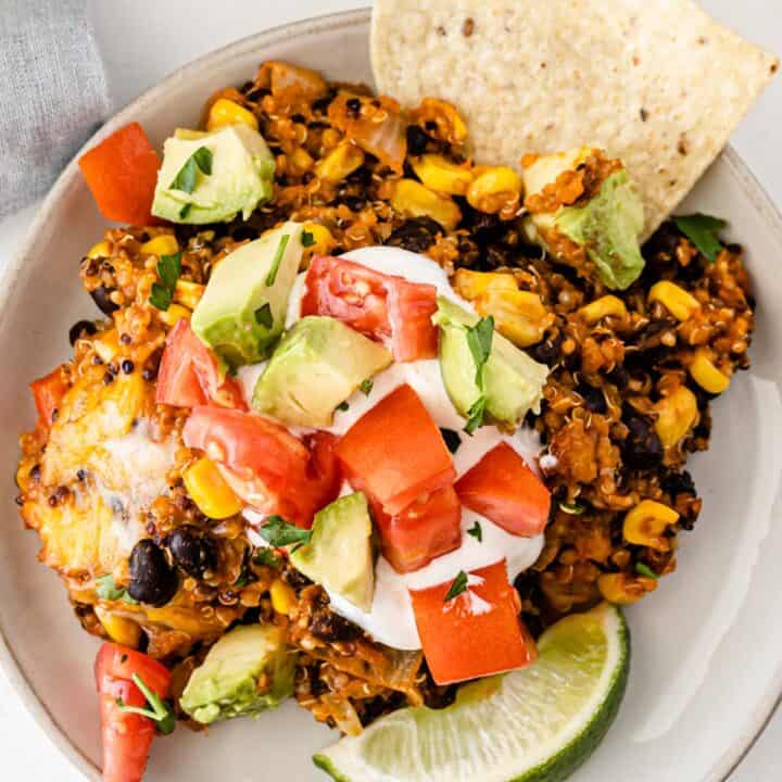 mexican quinoa cassserole topped with sour cream, tomatoes, and avocados