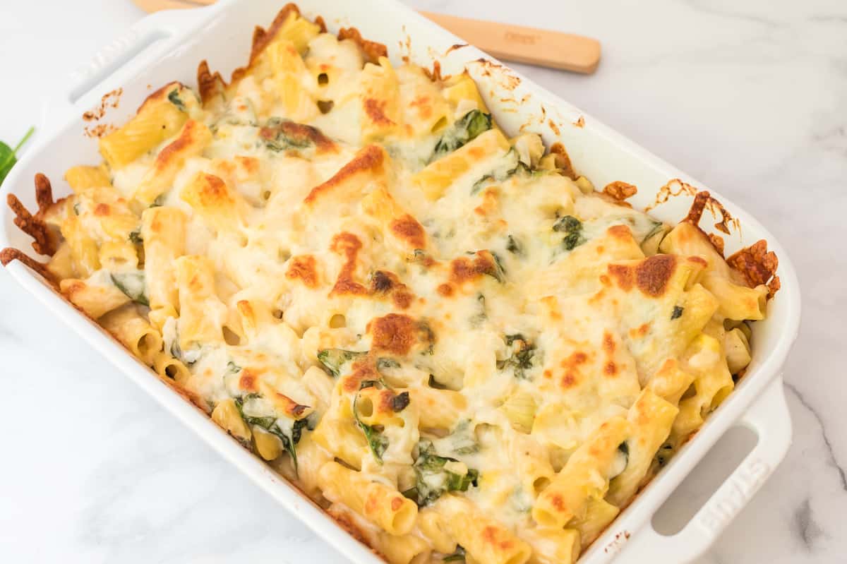 spinach artichoke pasta bake in a white baking dish