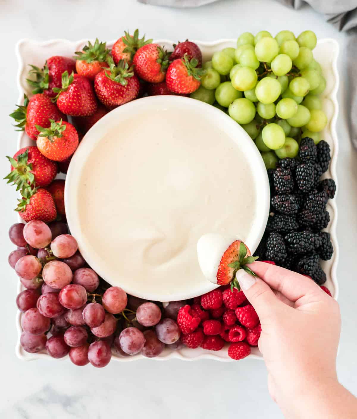 a tray full of fruit with a bowl of cream cheese yogurt dip