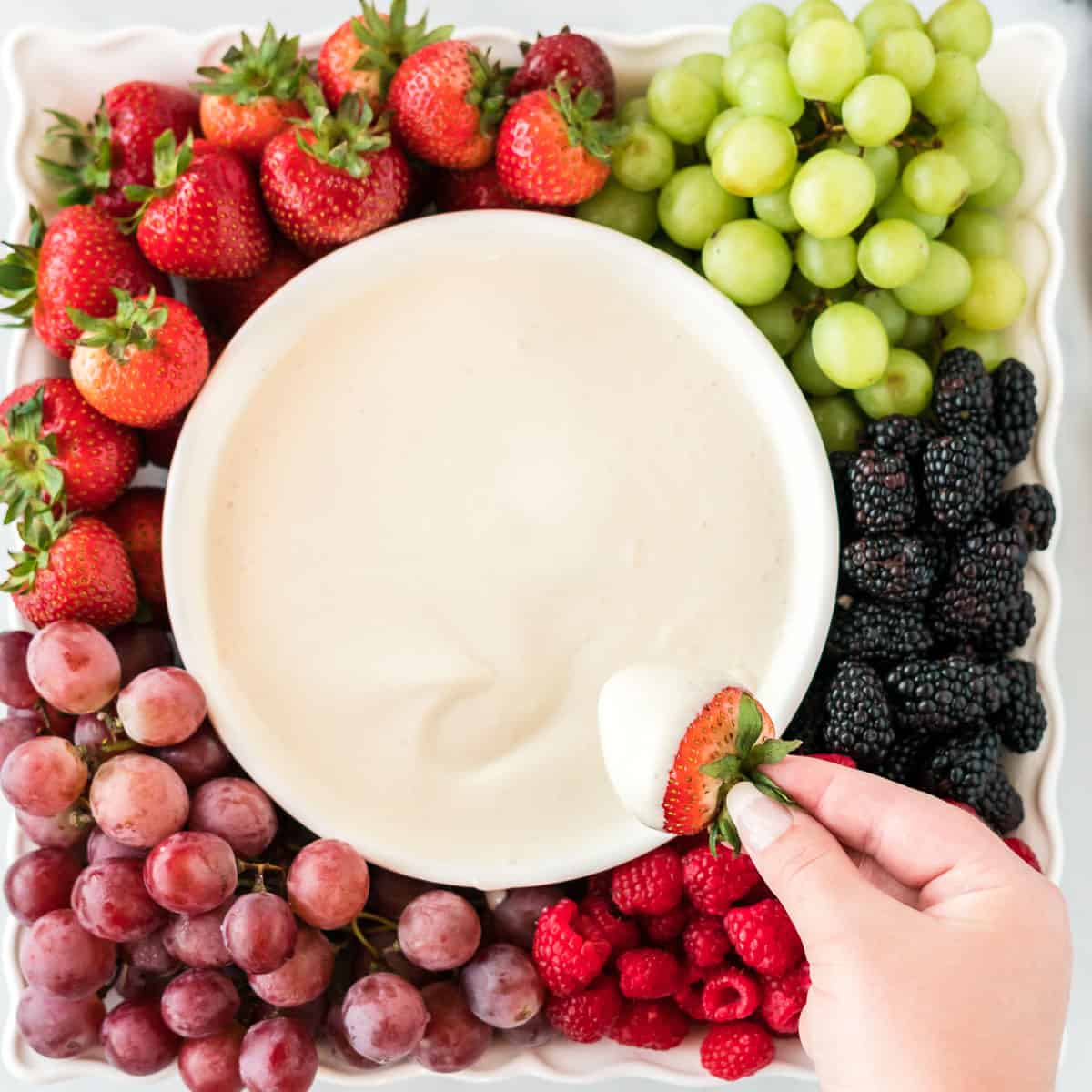 a tray full of fruit with a bowl of cream cheese yogurt dip