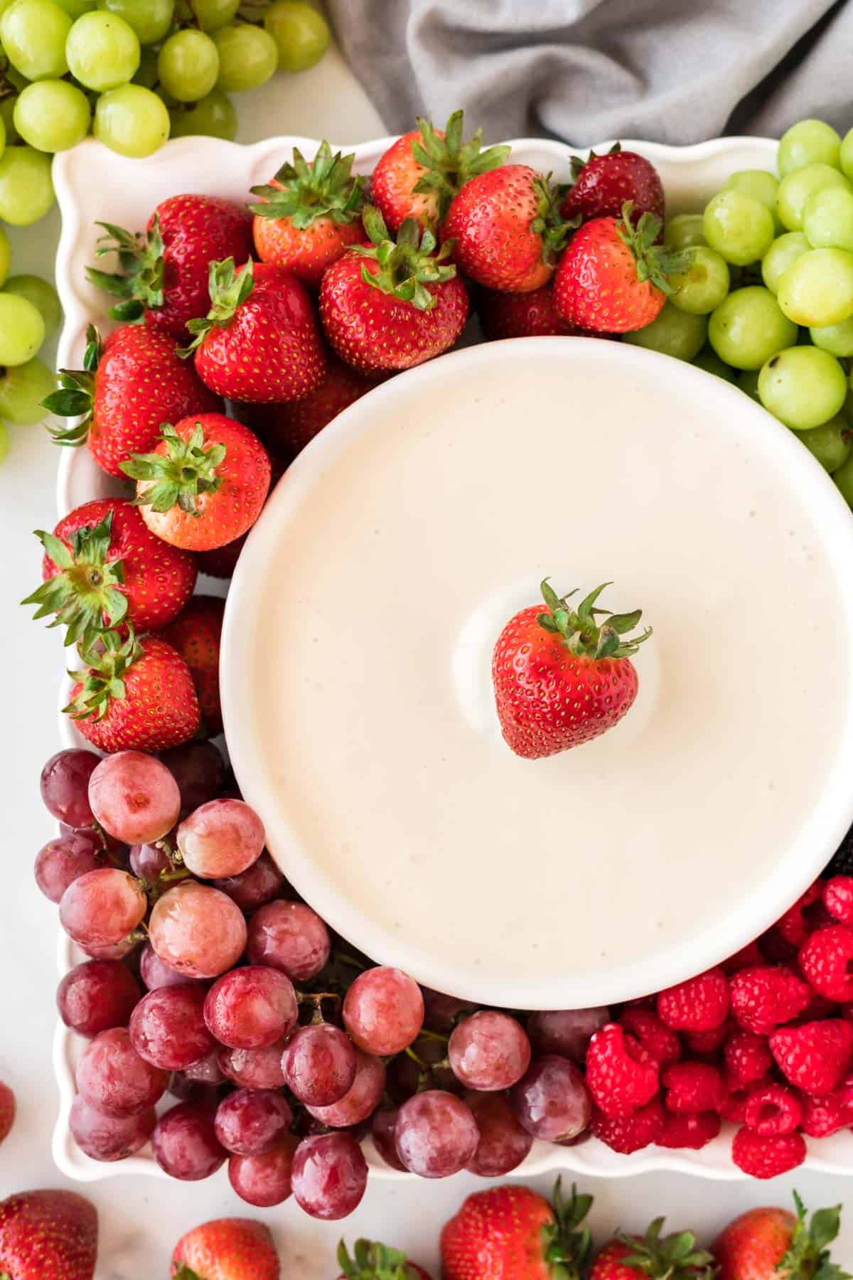 cream cheese dip in a bowl surrounded by fresh fruit on a platter