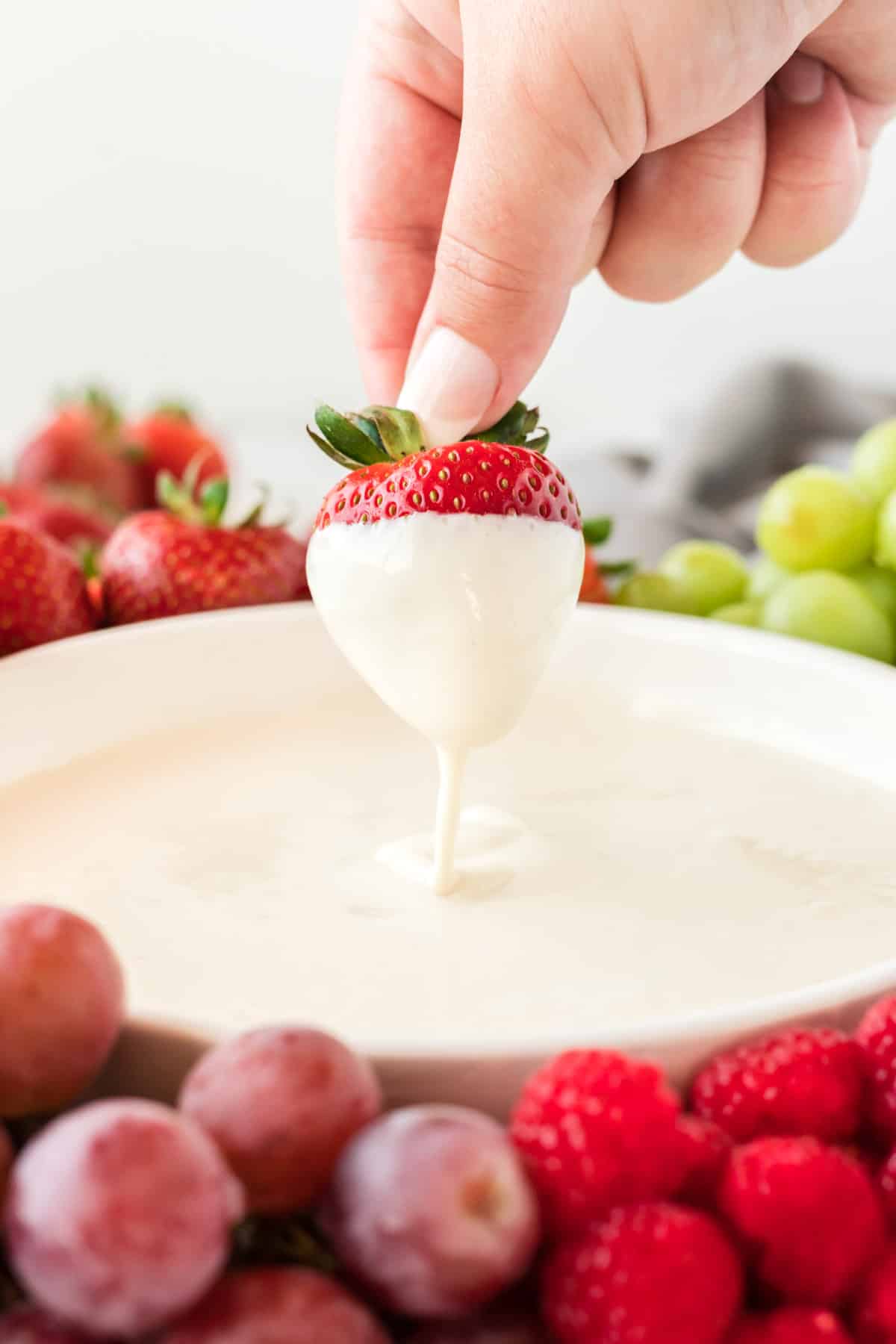 a strawberry being dipped into cream cheese yogurt dip