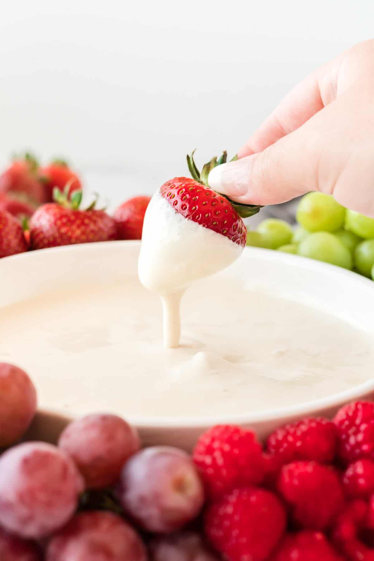 a strawberry being dipped into cream cheese yogurt dip