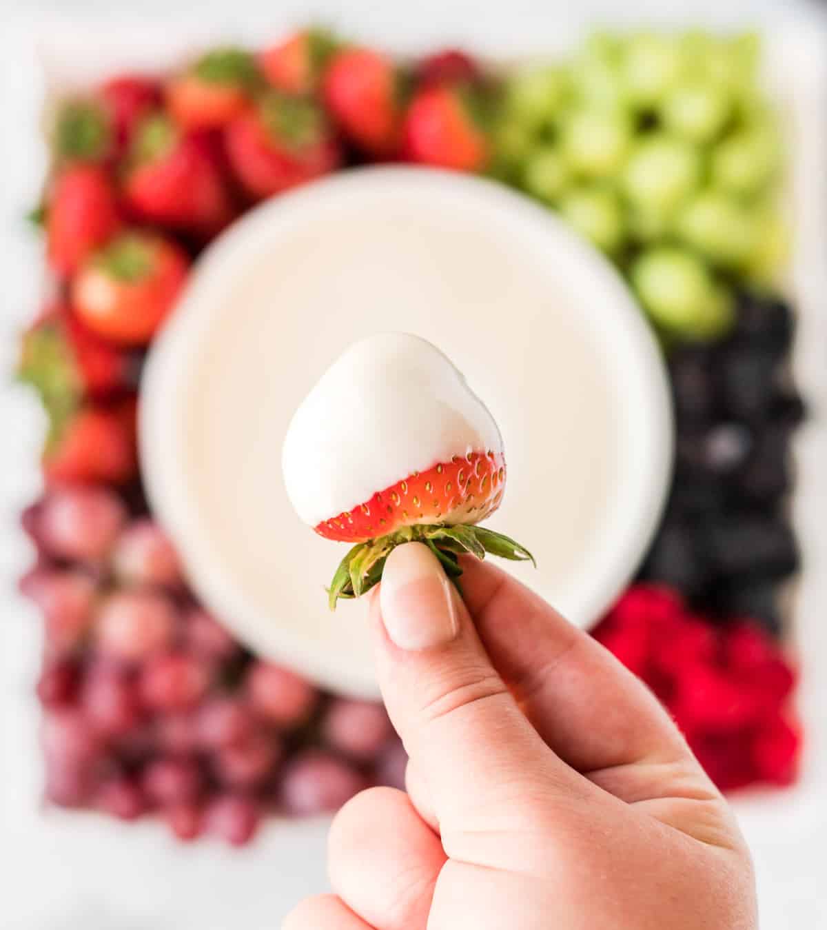 a strawberry being dipped into cream cheese yogurt dip