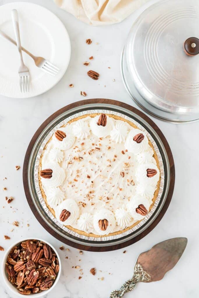 pecan cream pie decorated with whipped cream and pecans