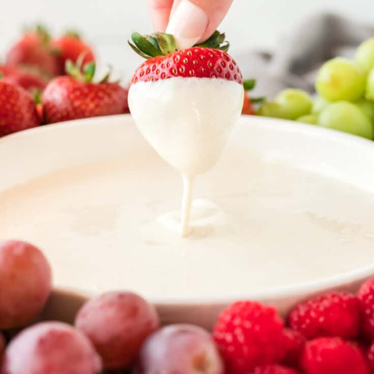 strawberry being dipped into cream cheese yogurt dip