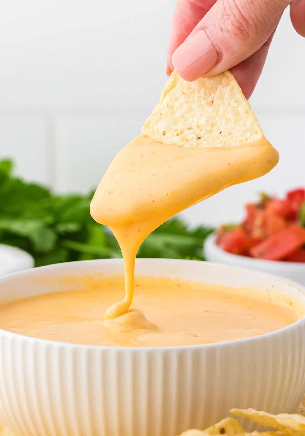 dipping a chip into nacho cheese sauce