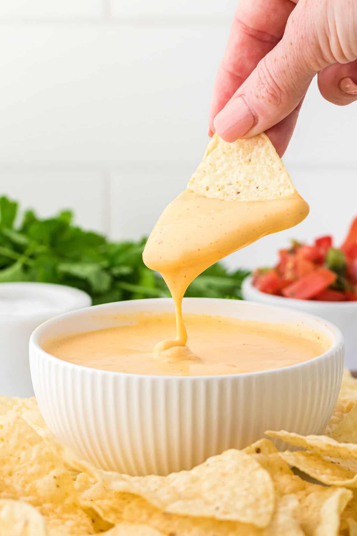 dipping a chip into nacho cheese sauce