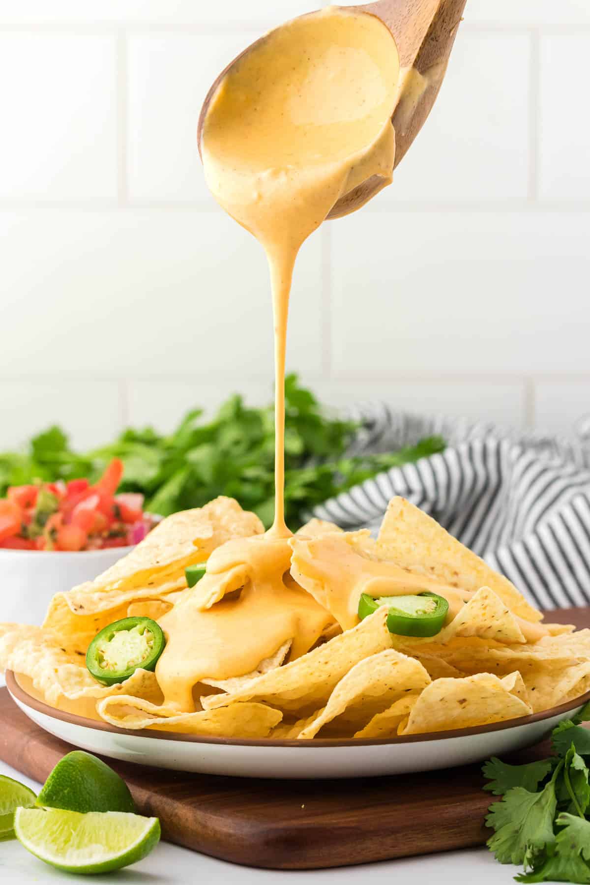 pouring nacho cheese sauce over chips