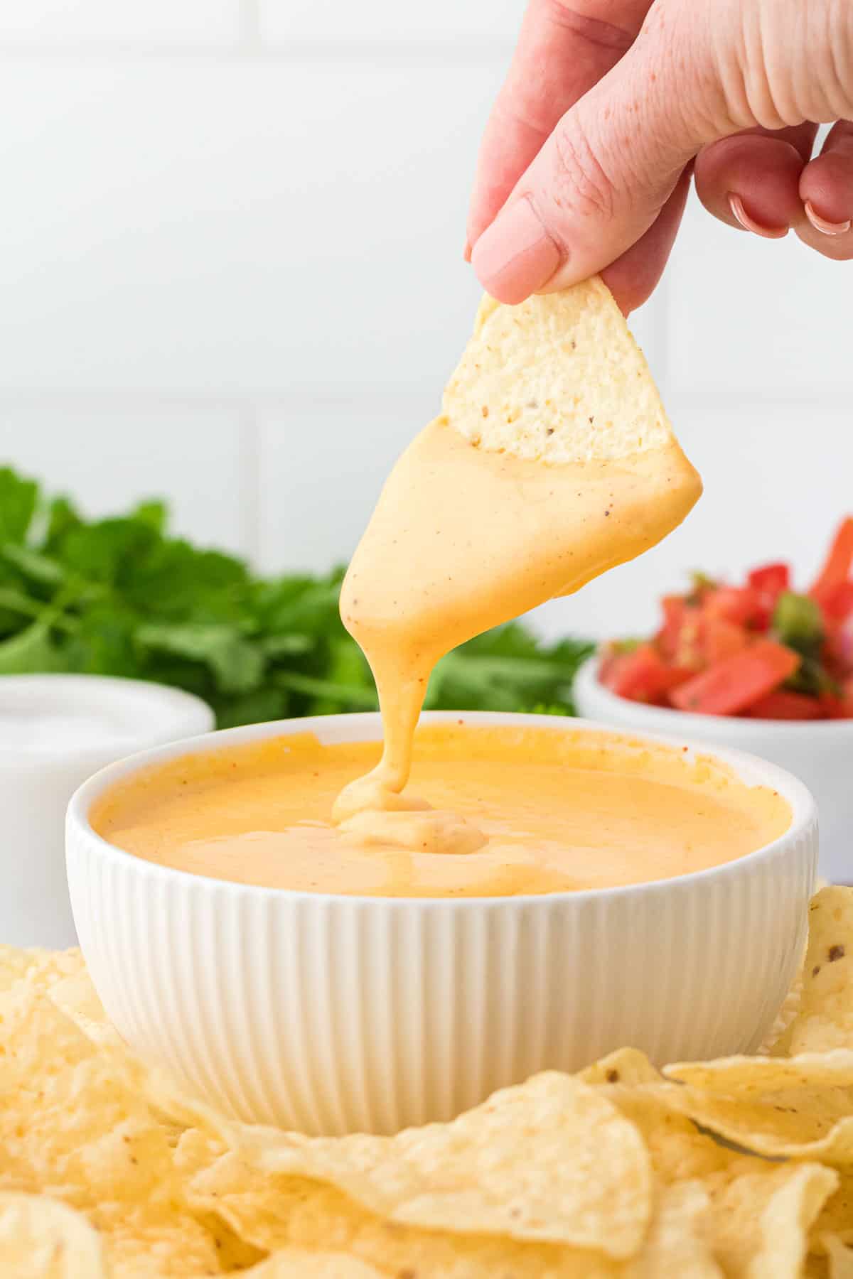 dipping a chip into nacho cheese sauce